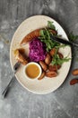 Grilled meat sausages and baked potatoes with vegetables on grey clay background. Royalty Free Stock Photo