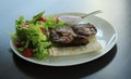 Grilled meat served with greens and pitta bread on white plate at the restaurant Royalty Free Stock Photo