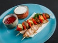 Grilled meat shish and vegetables kebab on skewers with sauce in plate over dark background. Healthy food. Hot meat dishes, Royalty Free Stock Photo