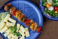 Grilled meat skewers with pasta on plate with vegetable sal