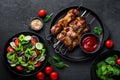 Grilled meat skewers, shish kebab and healthy vegetable salad of fresh tomato, cucumber, onion, spinach, lettuce and sesame on bla Royalty Free Stock Photo