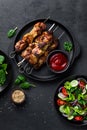 Grilled meat skewers, shish kebab and healthy vegetable salad of fresh tomato, cucumber, onion, spinach, lettuce and sesame on bla Royalty Free Stock Photo