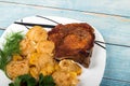 grilled meat with vegetables and herbs on a plate, wooden background