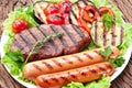 Grilled meat and vegetables over green leaves on white plate on the wooden table Royalty Free Stock Photo