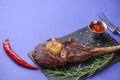 Grilled Medium rare barbecue Steak on bone with spices served on a rustic wooden board with sauce over blue background. Royalty Free Stock Photo