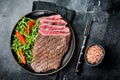 Grilled medium rare flank beef steak with salad in a plate. Black background. Top view Royalty Free Stock Photo