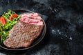 Grilled medium rare flank beef steak with salad in a plate. Black background. Top view. Copy space Royalty Free Stock Photo