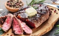 Grilled medium rare ribeye steak slices with melting butter on wooden serving board close up Royalty Free Stock Photo
