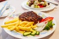 Grilled minced beef patty served with french fries and fresh vegetables on table Royalty Free Stock Photo