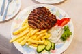 Grilled minced beef patty served with french fries and fresh vegetables on table Royalty Free Stock Photo