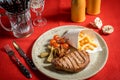 Grilled New York strip steak with bearnaise sauce, potato wedges, and cherry truss tomatoes. Garnished with parsley and