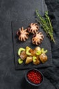 Grilled octopus. A side dish of roasted potatoes and celery. Black background. Top view. Space for text Royalty Free Stock Photo