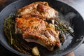 Grilled organic pork cutlets with herbs on bone in grill frying pan hot and hot oil just from fire, top view cooking bone with Royalty Free Stock Photo