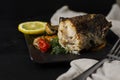 Grilled or oven baked hake fish on black plate. Keta diet and diet food concept. Royalty Free Stock Photo