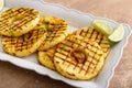 Grilled pineapple served with fresh lime wedges and whipped cream Royalty Free Stock Photo