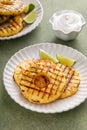 Grilled pineapple served with fresh lime wedges and whipped cream Royalty Free Stock Photo