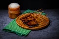 Grilled pork on bamboo skewers placed on a steel grill in a wooden tray with sticky rice in the cart, ready to serve Royalty Free Stock Photo