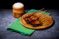 Grilled pork on bamboo skewers placed on a steel grill in a wooden tray with sticky rice in the cart, ready to serve Royalty Free Stock Photo