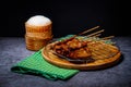 Grilled pork on bamboo skewers placed on a steel grill in a wooden tray with sticky rice in the cart, ready to serve Royalty Free Stock Photo