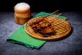 Grilled pork on bamboo skewers placed on a steel grill in a wooden tray with sticky rice in the cart, ready to serve Royalty Free Stock Photo