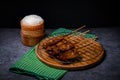 Grilled pork on bamboo skewers placed on a steel grill in a wooden tray with sticky rice in the cart, ready to serve Royalty Free Stock Photo