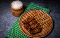 Grilled pork on bamboo skewers placed on a steel grill in a wooden tray with sticky rice in the cart, ready to serve Royalty Free Stock Photo