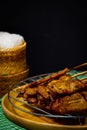 Grilled pork on bamboo skewers placed on a steel grill in a wooden tray with sticky rice in the cart, ready to serve Royalty Free Stock Photo