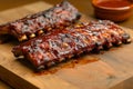 Grilled pork bbq ribs served with cherry tomatoes, basil and barbeque sauce on wooden cutting board on wood board. Royalty Free Stock Photo