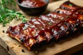 Grilled pork bbq ribs served with cherry tomatoes, basil and barbeque sauce on wooden cutting board on wood board. Royalty Free Stock Photo