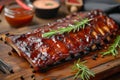 Grilled pork bbq ribs served with cherry tomatoes, basil and barbeque sauce on wooden cutting board on wood board. Royalty Free Stock Photo