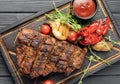 Grilled pork bbq ribs served with cherry tomatoes, pepper and barbeque sauce on wooden cutting board over dark Royalty Free Stock Photo