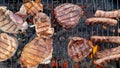 Grilled pork, beef and chicken steaks and sausages grilled on a charcoal grill. View from above. Summer holidays and vacations.