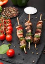 Grilled pork and chicken kebab with paprika on stone chopping board with salt, pepper and tomatoes on black background. Fresh Royalty Free Stock Photo