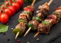 Grilled pork and chicken kebab with paprika on stone chopping board with salt, pepper and tomatoes on black background Royalty Free Stock Photo