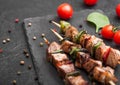 Grilled pork and chicken kebab with paprika on stone chopping board with salt, pepper and tomatoes on black background Royalty Free Stock Photo