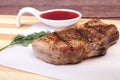 Grilled pork chop with Cranberry sauce on plate on wooden board Royalty Free Stock Photo