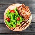 Grilled pork chop steak with fresh vegetable salad, tomatoes and sauce on wooden cutting board Royalty Free Stock Photo