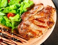 Grilled pork chop steak with fresh vegetable salad, tomatoes and sauce on wooden cutting board Royalty Free Stock Photo