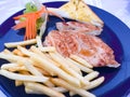 Grilled Pork chop Steak with gravy sauce, there are French fries and Salad with cream sauce on side dishes Royalty Free Stock Photo