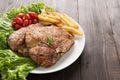 Grilled pork chop steak and vegetables with french fries on wood Royalty Free Stock Photo
