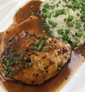 Grilled pork chops with peas rice, chives and gravy.