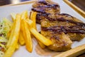 Grilled pork with french fries and salad on wooden plate