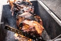 Grilled pork meat charred to black above a metalic grill, barbecueing