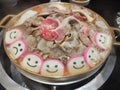 Grilled pork and meatballs with a smiley face on a brass pan