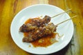 Grilled pork neck stabbing in wooden stick dressing spicy sauce on dish