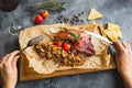 Grilled pork ribs, buckwheat with mushroom and tomatoes on vintage wooden cutting board and woman hands with cutlery. Close up vie Royalty Free Stock Photo