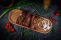 Grilled pork ribs on a dark stone table with vegetables, cream and tomato sauce. Served on a wooden board. Fast food restaurant, d Royalty Free Stock Photo