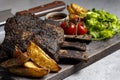 grilled pork ribs with french fries and vegetables on a wooden board Royalty Free Stock Photo