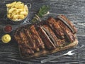 Grilled pork ribs with sauce on a cutting board, french fries