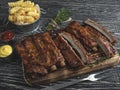 Grilled pork ribs with sauce on a cutting board, french fries Royalty Free Stock Photo